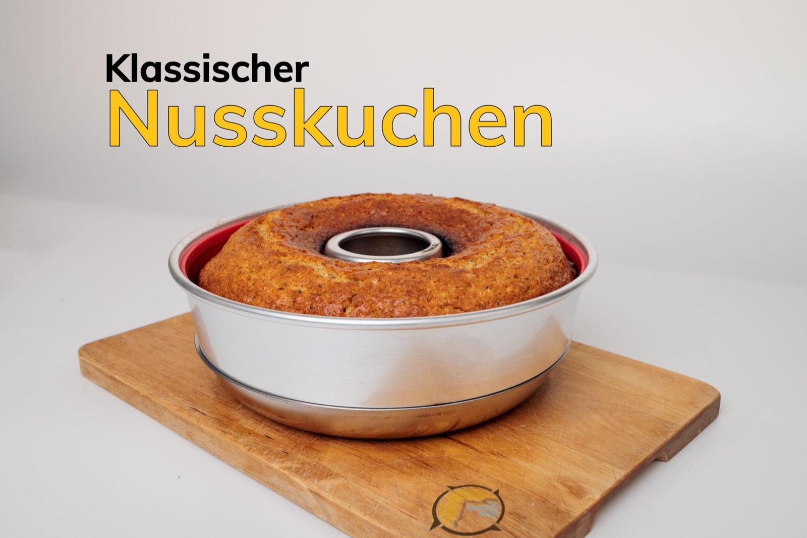 Nusskuchen in der roten Silikonform des Omnia auf einem Holzbrett, deutlich die Ringform mit dem Loch in der Mitte