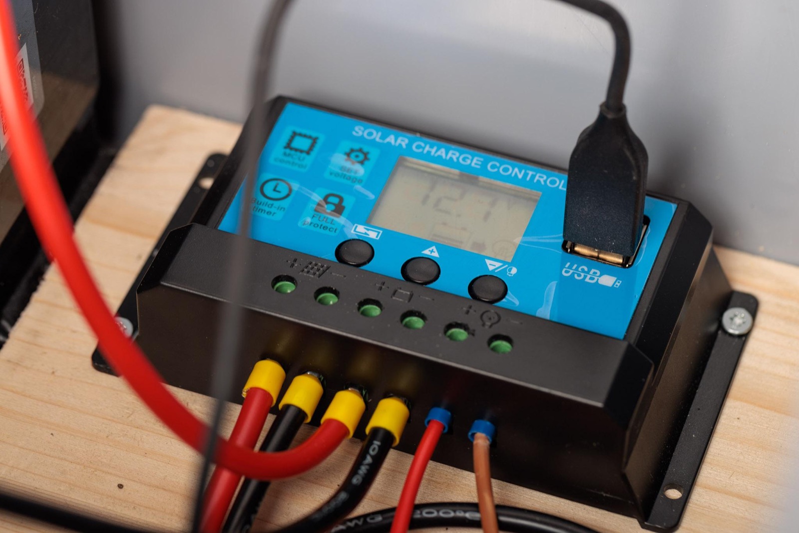 Der Laderegler auf dem Holzbrett, Panel- und Batteriekabel angeschlossen. Das Display zeigt die Batteriespannung.